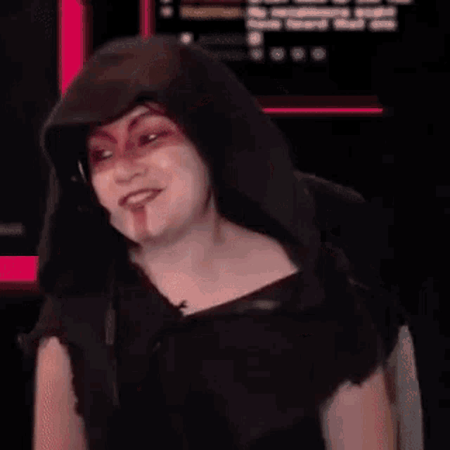 a woman wearing a headset and a hood is holding a cell phone .
