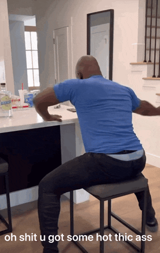 a man in a blue shirt is sitting on a stool with the caption oh shit u got some hot thic ass