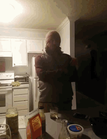 a man is standing in a kitchen with a carton of apple juice
