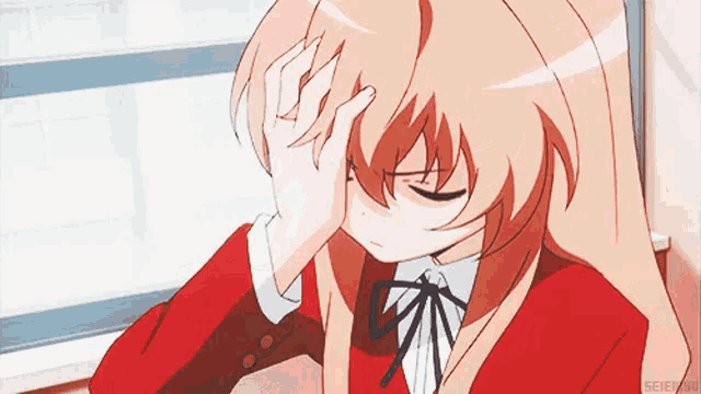 a girl is sitting in front of a window and covering her face with her hand .