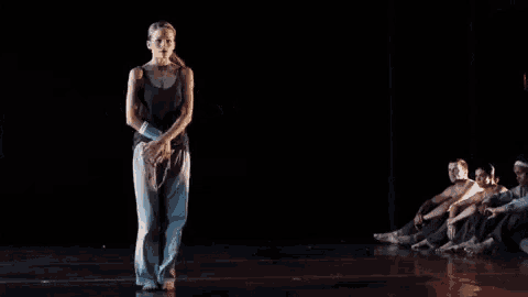a woman in a black tank top and blue pants is dancing