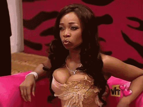 a woman is sitting on a pink couch with a vh1 logo on the wall behind her
