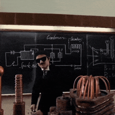 a man wearing sunglasses stands in front of a blackboard that says condensers