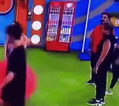 a man in a red shirt is standing next to a man in a black shirt in a room with a green floor .