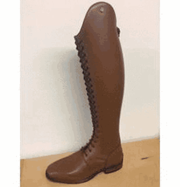 a pair of brown riding boots is sitting on a wooden table .