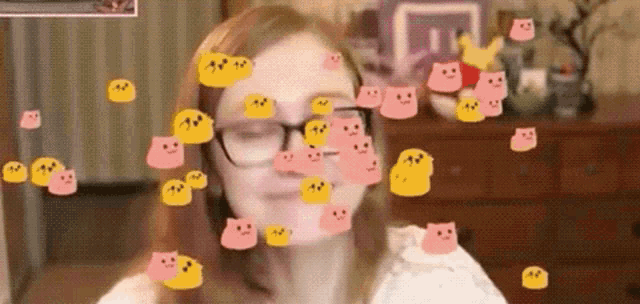 a woman wearing glasses is surrounded by a bunch of smiley faces .