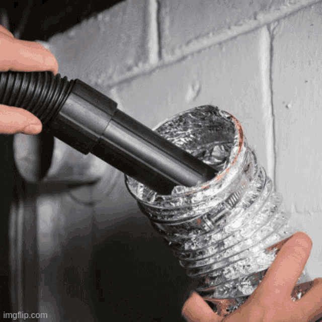 a person is using a vacuum cleaner to clean aluminum ducting