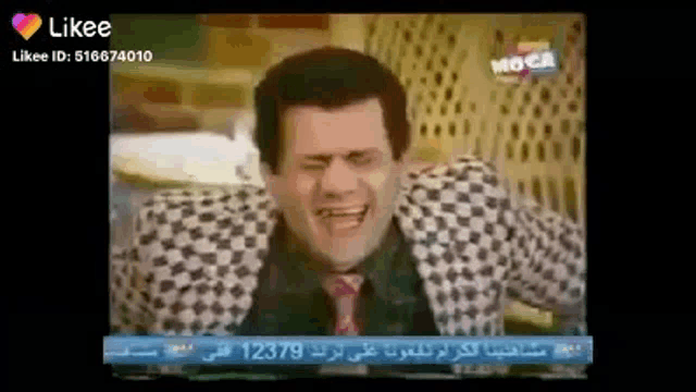 a man in a checkered suit and tie is making a funny face on a television screen .