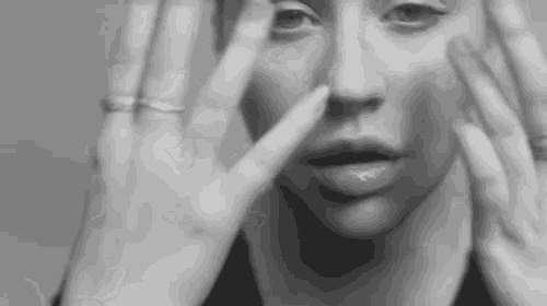 a black and white photo of a woman covering her face with her hands