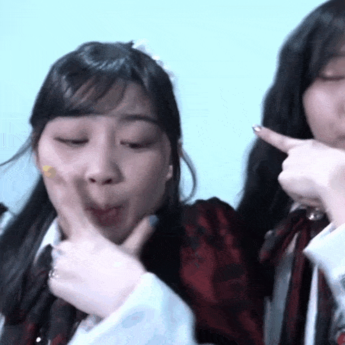 two girls are making funny faces and one is pointing