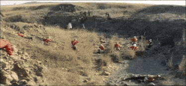 a group of people in red jumpsuits are standing in the dirt