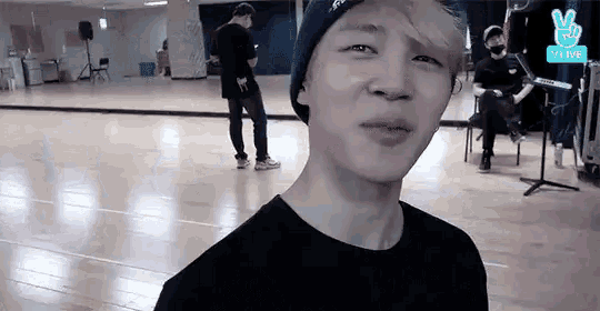 a young man wearing a beanie and a black shirt is standing on a wooden floor in a dance studio .