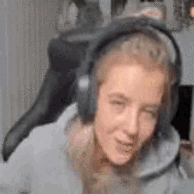 a woman wearing headphones is sitting in a chair and making a funny face .