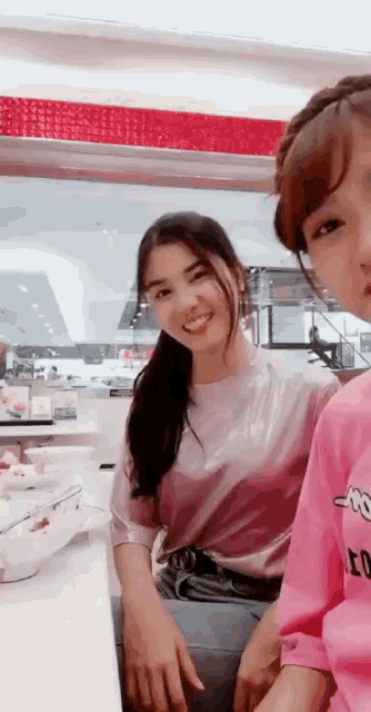a girl in a pink shirt is sitting next to a girl in a pink shirt
