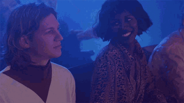 a man and a woman are sitting in a dark room with a blue light behind them
