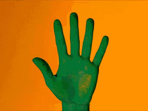 a green hand is covering a woman 's face against an orange background