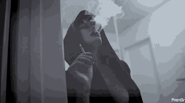 a woman is smoking a cigarette in a black and white photo with the word premier on the bottom