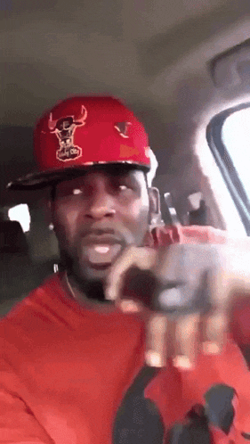 a man wearing a red hat and a red shirt is pointing at the camera
