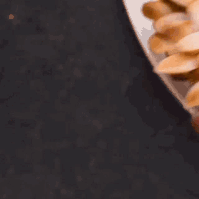 a person is holding a cookie in the shape of a sunflower made of almonds .