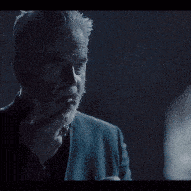 a man with gray hair and a beard is smoking a cigarette