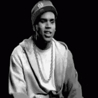 a black and white photo of a man wearing a hat and a hoodie .