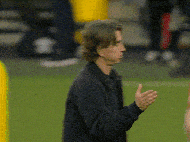 a man in a black jacket is standing on a field