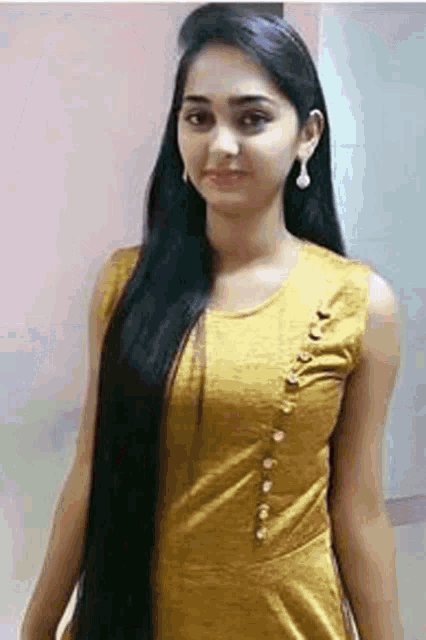 the woman is wearing a yellow dress and has very long hair .