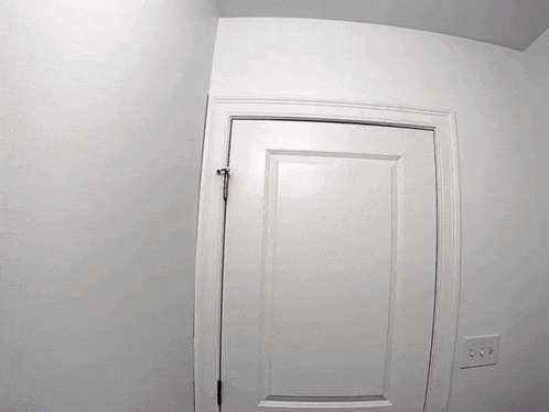 a white door is open to a room with a light switch on the wall