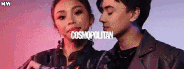 a man and a woman are standing next to each other in front of a cosmopolitan ad .