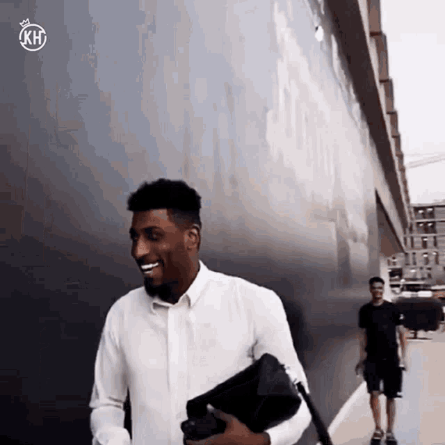 a man in a white shirt is smiling while holding a black purse
