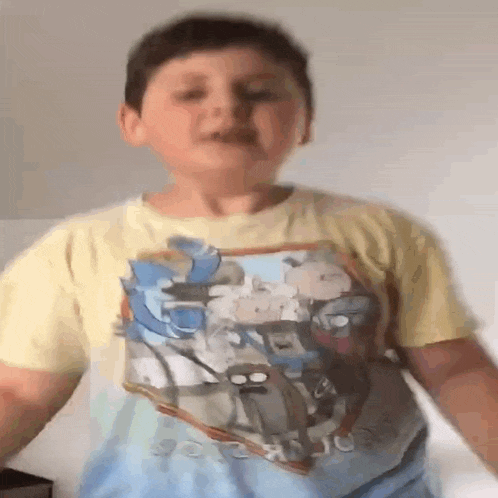 a young boy wearing a t-shirt with a picture of cartoon characters on it
