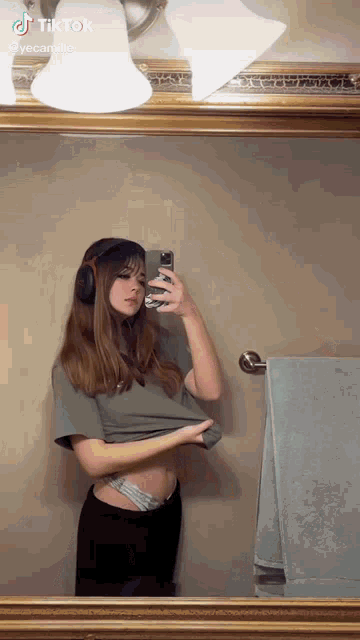 a woman is taking a selfie in front of a mirror .