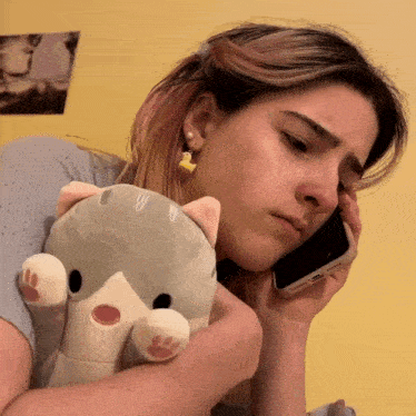 a woman is holding a stuffed animal while talking on a cell phone