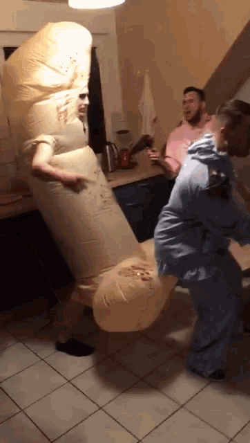 a man in an inflatable penis costume stands next to a man in a pink shirt