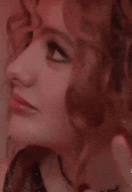 a close up of a woman 's face with red hair and a choker necklace .