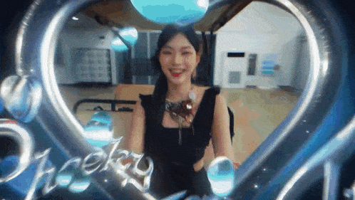 a woman in a black dress is standing in a room with a heart shaped frame around her .