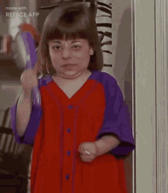 a little girl in a red and purple dress is holding a brush .