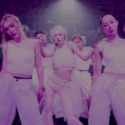 a group of women are dancing on a stage in purple light