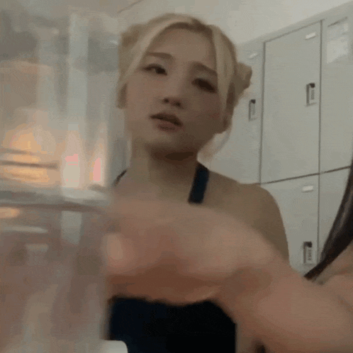 a woman is holding a glass of water in front of lockers .