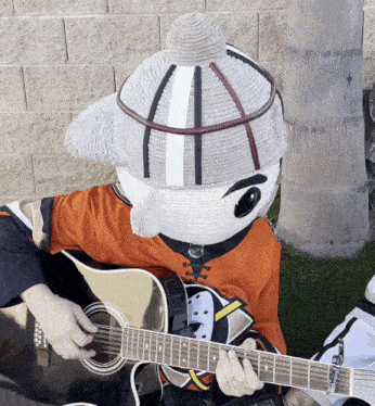a mascot is playing a guitar and wearing an orange shirt