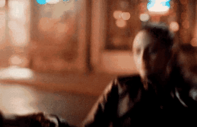 a blurry picture of a man holding another man 's hand in front of a window .