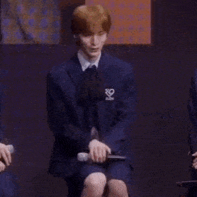 a man in a suit and tie is sitting on a stool with his legs crossed .