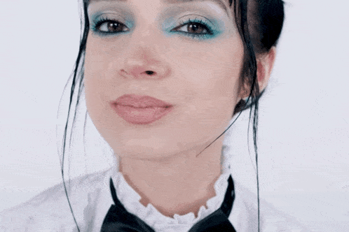 a woman with blue eye shadow and a black bow tie