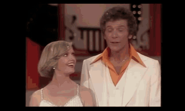 a man and a woman are standing next to each other on a stage and laughing .
