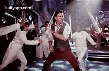 a man is holding a sword in his hand while dancing with a group of people .