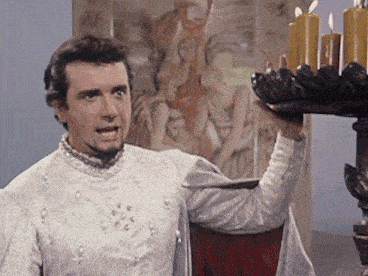 a man in a white costume holds a tray of candles in front of a painting