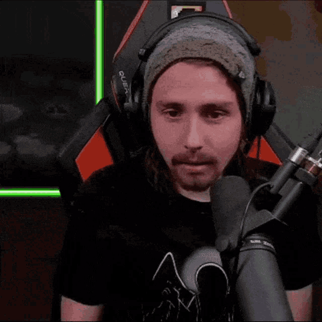 a man wearing headphones and a beanie is sitting in front of a microphone with the word combinen written on the screen