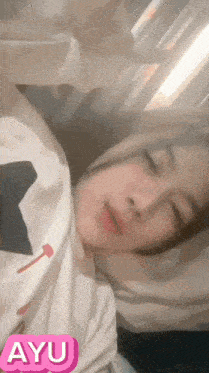 a girl is laying in bed with a sticker that says ayu on it