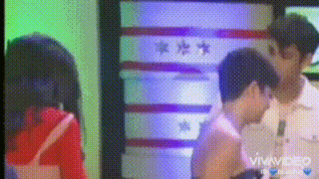 a couple of people are standing next to each other in front of a television screen .