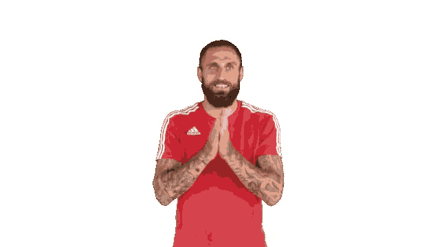 a man with a beard wearing a red adidas shirt is praying